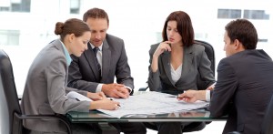 Four serious engineers looking at plans sitting at a table